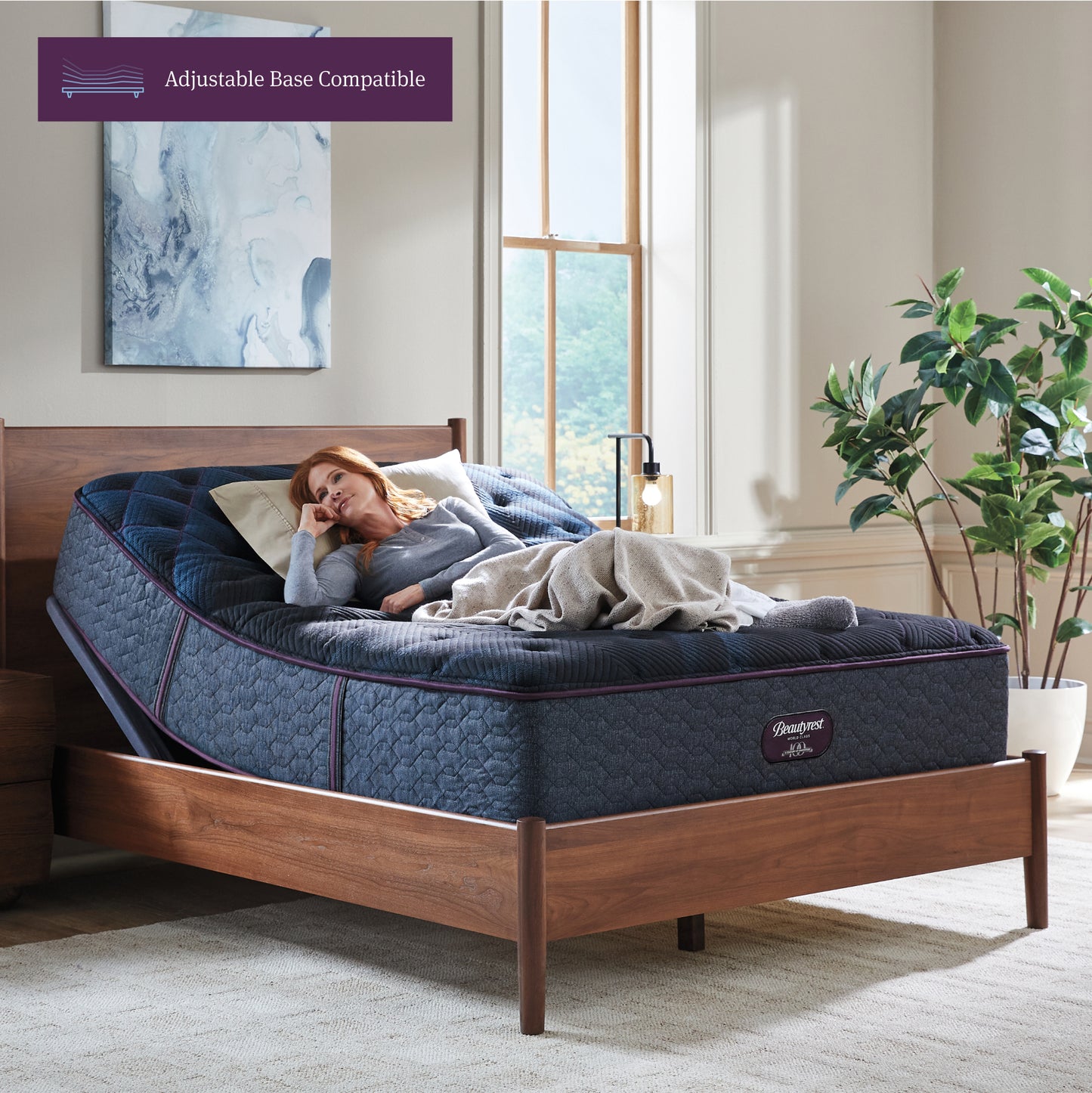 Woman lying on a blue mattress in a bedroom with a wooden bed frame.